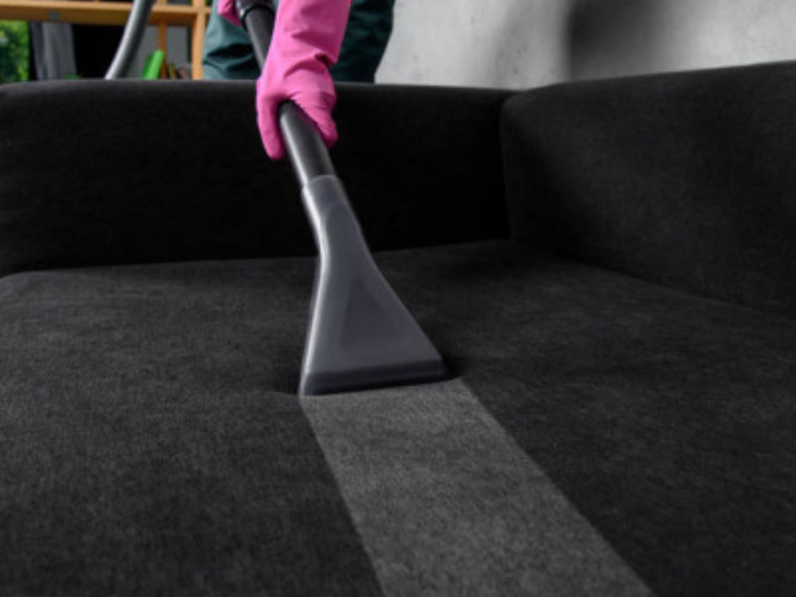 An extraction tool drawing a clean lane across a dark sofa